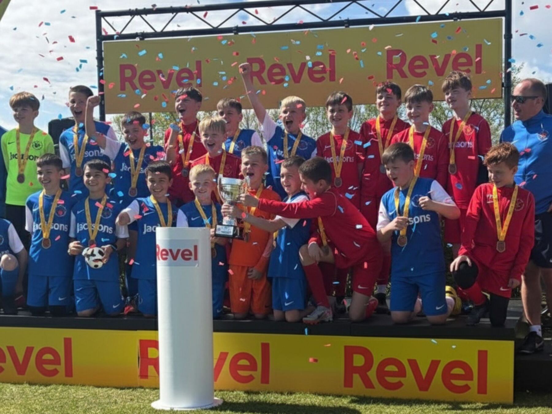 A junior football team on the podium with medals and trophy